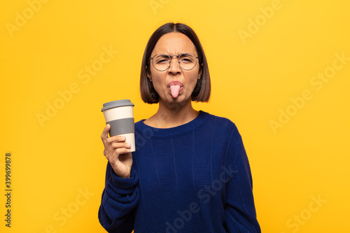 young latin woman feeling disgusted and irritated, sticking tongue out, disliking something nasty and yucky