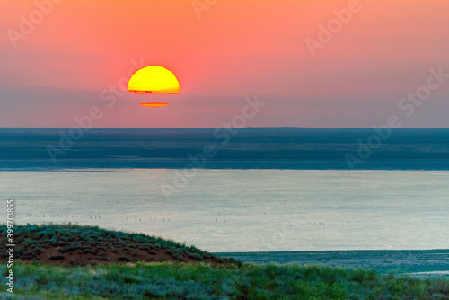 Beautiful bright red sunset over the lake and steppe