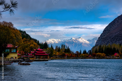 blue water lake with red huts and snow mountains in background, autumn landscape photographs of skardu, Karakorum range  photo