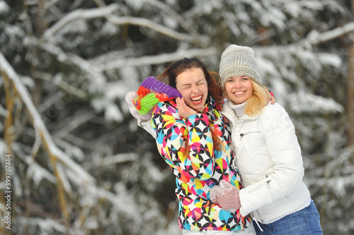 Two girls in the winter forest emotionally hug and smile.Happy women hug and Express joy photo