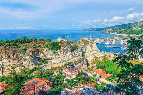 Tropea town aerial view of port marina, stone rocks and cliffs and Tyrrhenian sea with turquoise water and mountains in horizon, Vibo Valentia, Calabria, Southern Italy photo