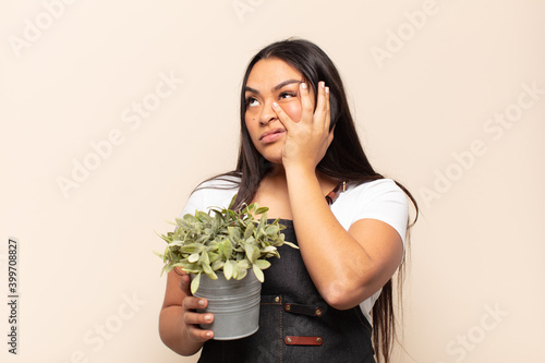 young latin woman feeling bored, frustrated and sleepy after a tiresome, dull and tedious task, holding face with hand