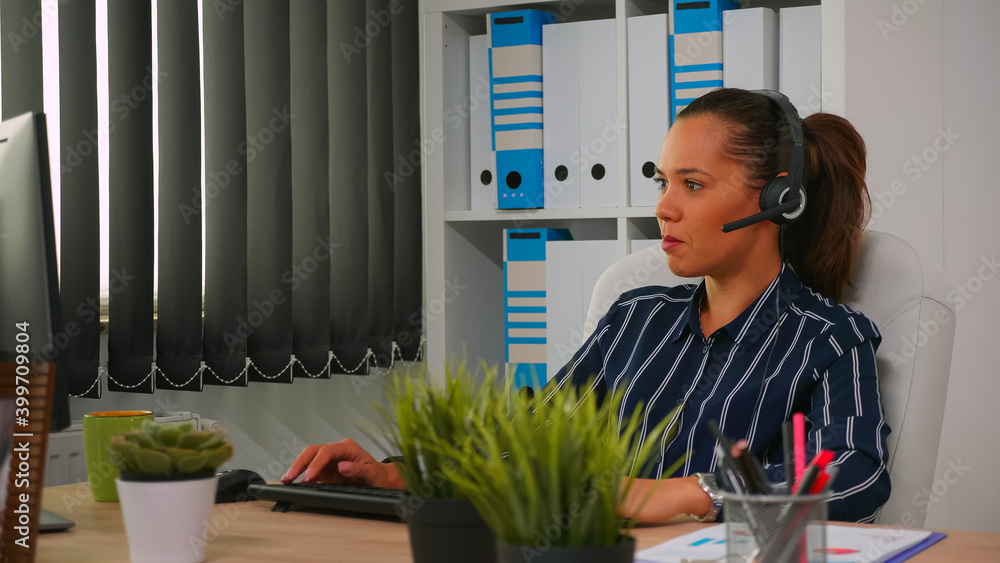 Hispanic businesswoman with headset working in modern business office making teleappointment using modern technology. Freelancer discussing with customer in financial company building Hispanic businesswoman with headset working in modern business office making teleappointment using modern technology. Freelancer discussing with customer in financial company building