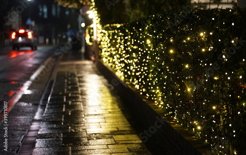 The sidewalk at night after the rain illuminated by the lights