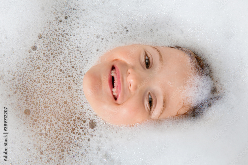 Smiling toothless girl lying in bubble bath Smiling toothless girl lying in bubble bath