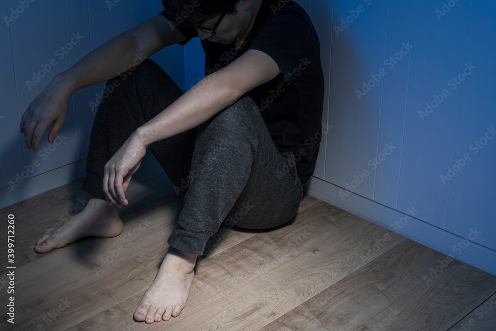 暗い部屋で床に座っている男性 暗い部屋で床に座っている男性