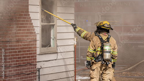 Firefighters break a window of a structure fire