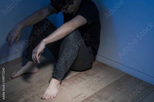 暗い部屋で床に座っている男性