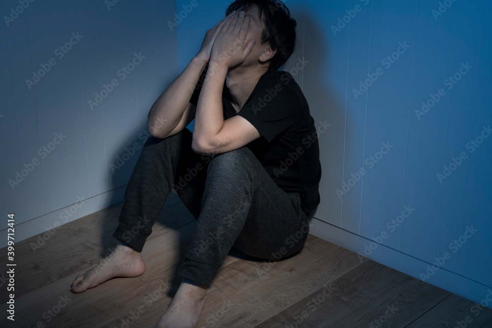 暗い部屋で床に座っている男性 暗い部屋で床に座っている男性
