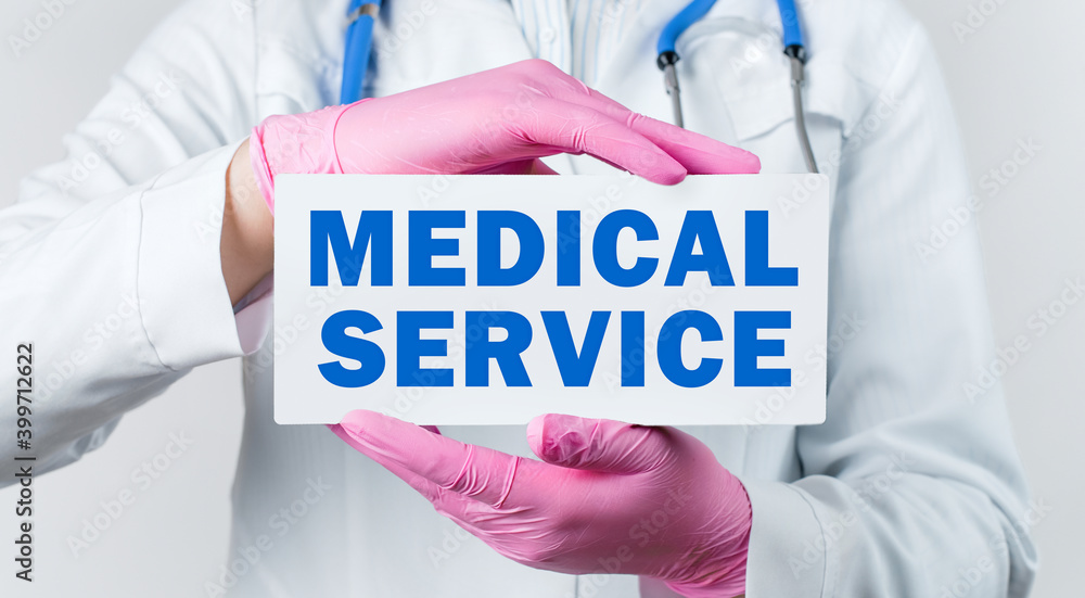 Cropped view of female doctor in a white coat and pink sterile gloves holding a card with words - medical service Cropped view of female doctor in a white coat and pink sterile gloves holding a card with words - medical service