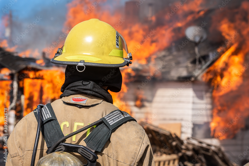 Fototapeta premium Firefighter watches a home burn