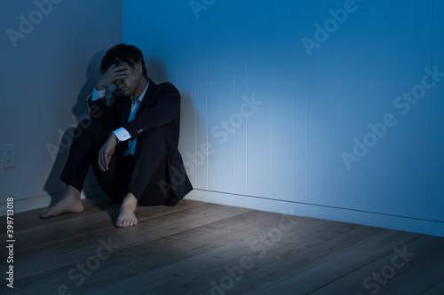 暗い部屋で床に座り込んだビジネスマン
