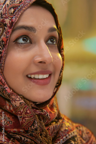 A WOMAN WITH HEAD COVERED WITH SHAWL LOOKING ABOVE AND SMILING	 photo