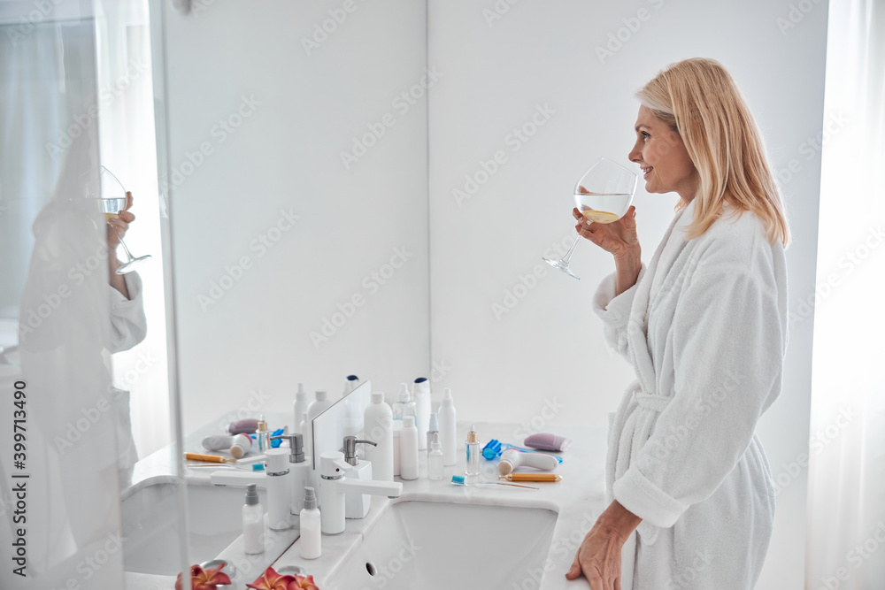 Happy attractive blonde woman looking in the mirror in room indoors Happy attractive blonde woman looking in the mirror in room indoors