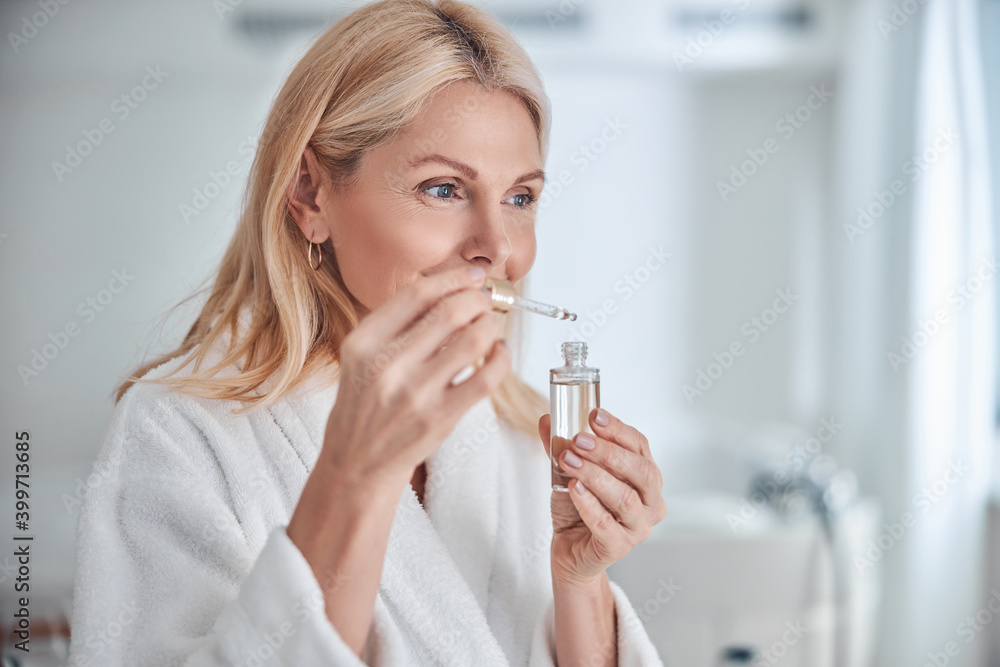 Pretty elegant female with face skin care in hand in bathroom Pretty elegant female with face skin care in hand in bathroom