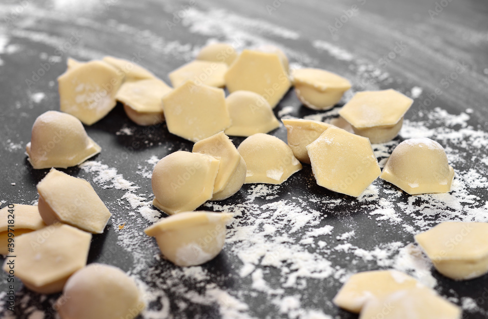 Dumplings, ravioli close-up, hexagonal shape of dough on a black table. Dusted with flour. Dumplings, ravioli close-up, hexagonal shape of dough on a black table. Dusted with flour.