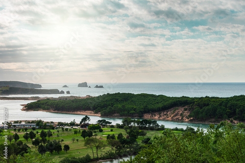 green coastline at sea with golf course and cloudy sky