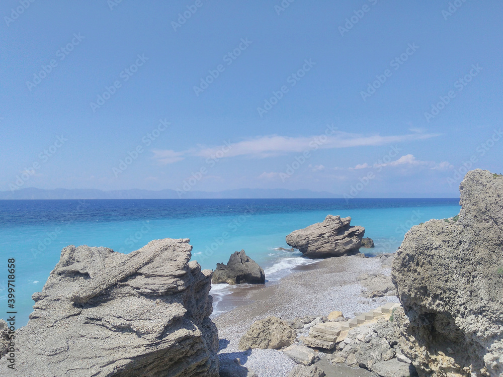 Beautiful Aegean seascape: rocks on the beach, blue sea. Rhodes, Greece