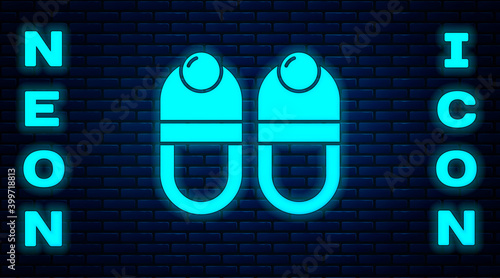 Glowing neon Slippers icon isolated on brick wall background. Flip flops sign. Vector.