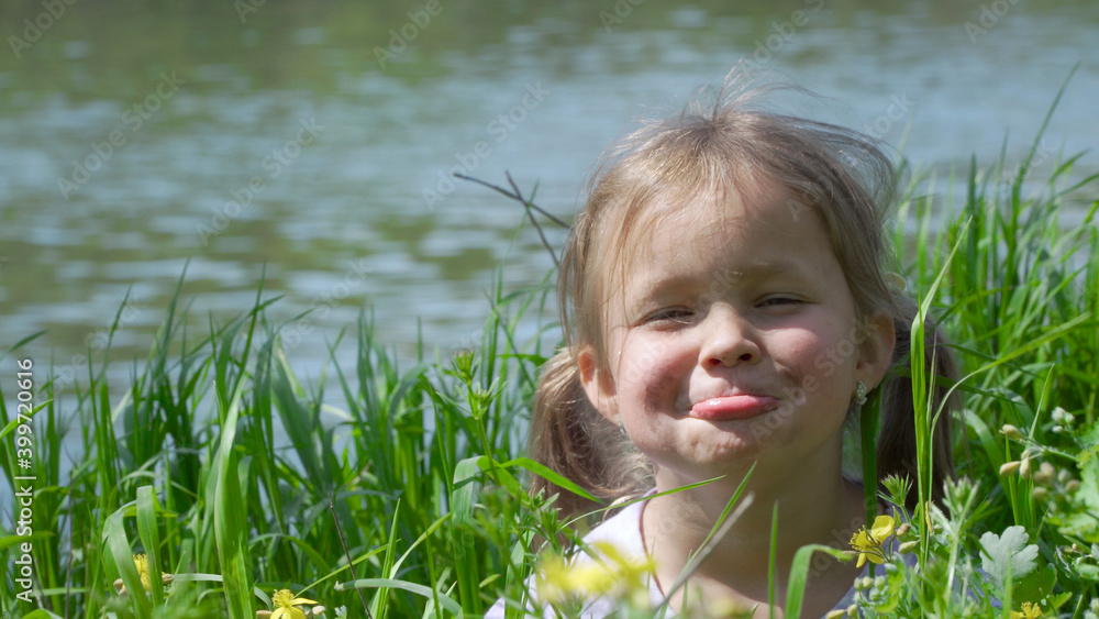 Portrait of a smiling little girl. Baby girl sitting in tall grass. Tiny kid have fun, enjoy nature outdoors. Portrait of a smiling little girl. Baby girl sitting in tall grass. Tiny kid have fun, enjoy nature outdoors.