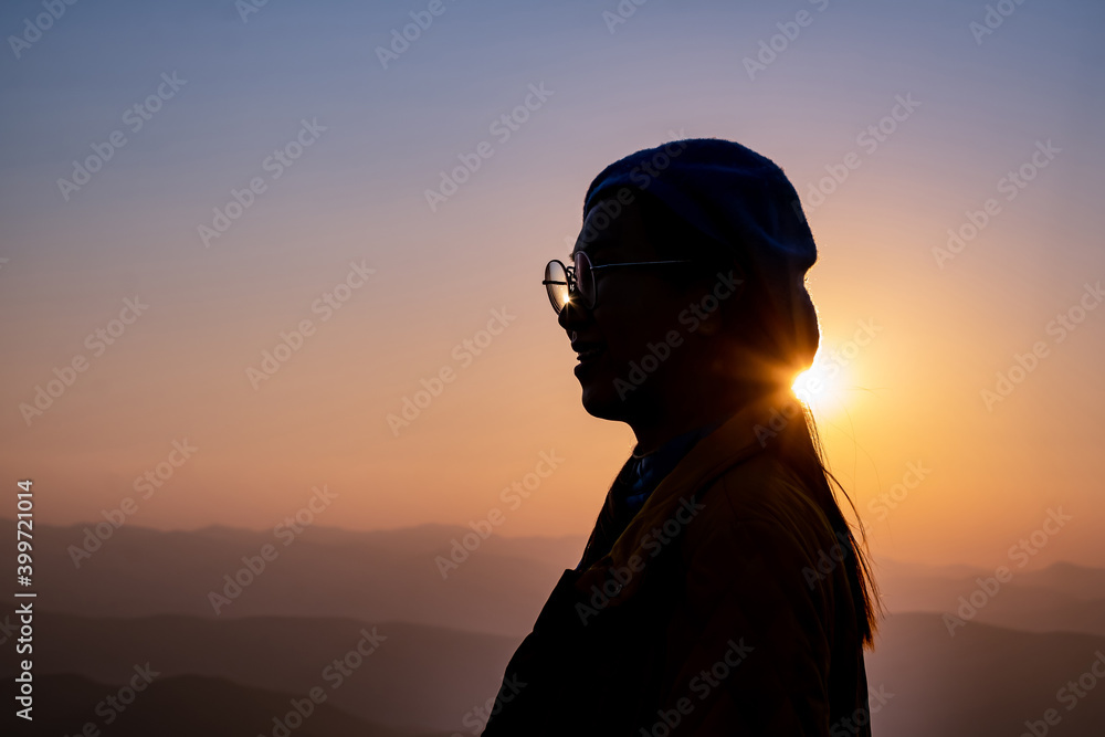 Silhouette of proud and happy woman on the mountains with the sea mist and sunrise in the morning.