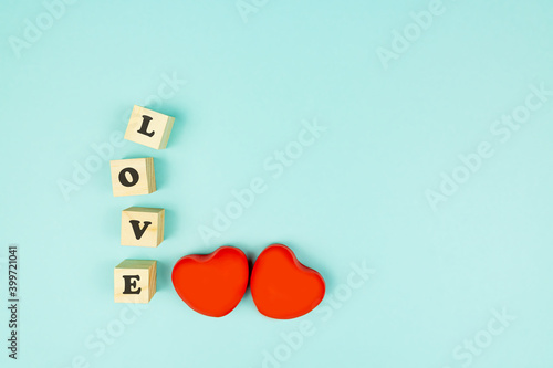 Red heart and wooden cubes with text LOVE on blue background. Creative flat lay with copy space. Festive greeting card for St Valentines day.