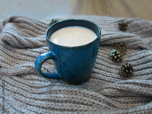Obraz na płótnie warm blue mug with milk and warm knitted scarf