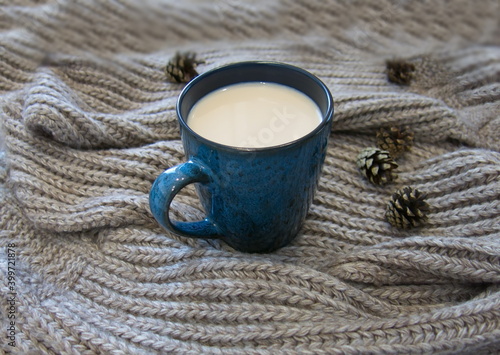 Fotografie hot milk drink in a blue mug and a warm scarf