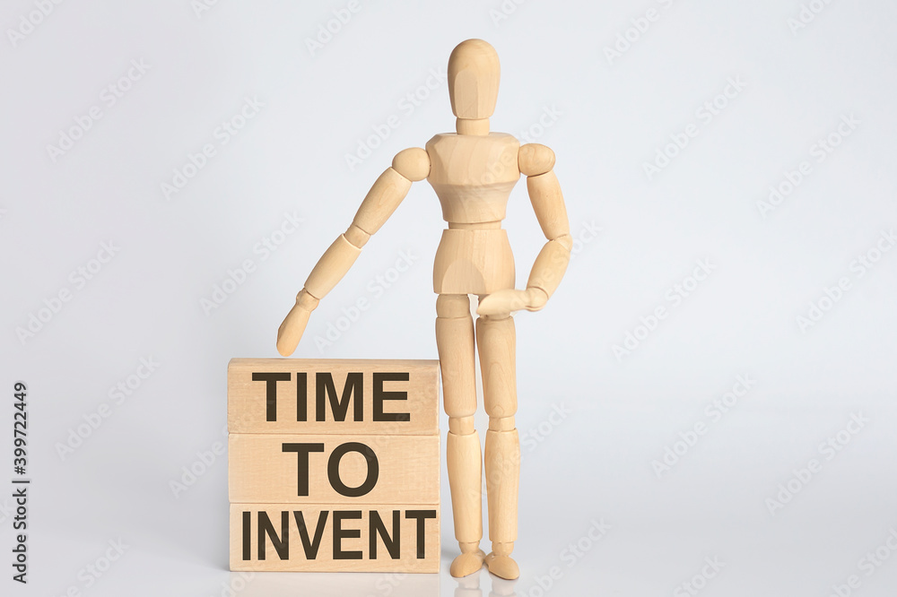 Wooden man shows with a hand text TIME TO INVENT concept on the wooden block Wooden man shows with a hand text TIME TO INVENT concept on the wooden block