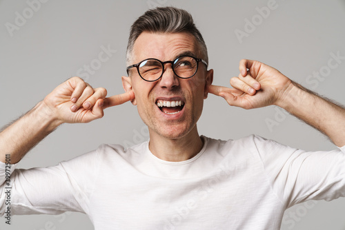 Irritated upset man blocking ears isolated