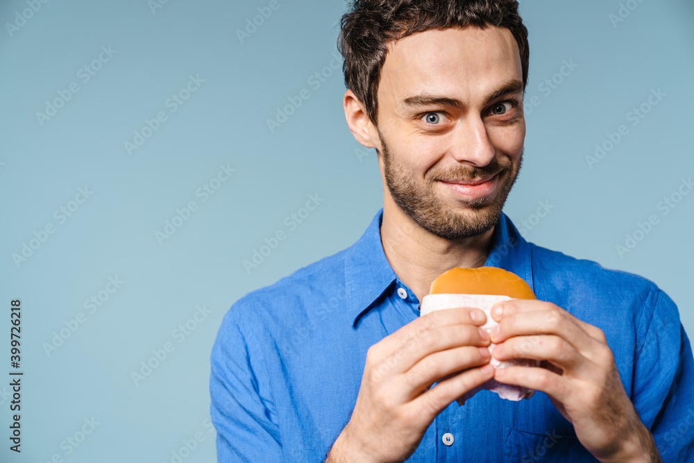 Joyful handsome guy smiling while posing with hamburger Joyful handsome guy smiling while posing with hamburger