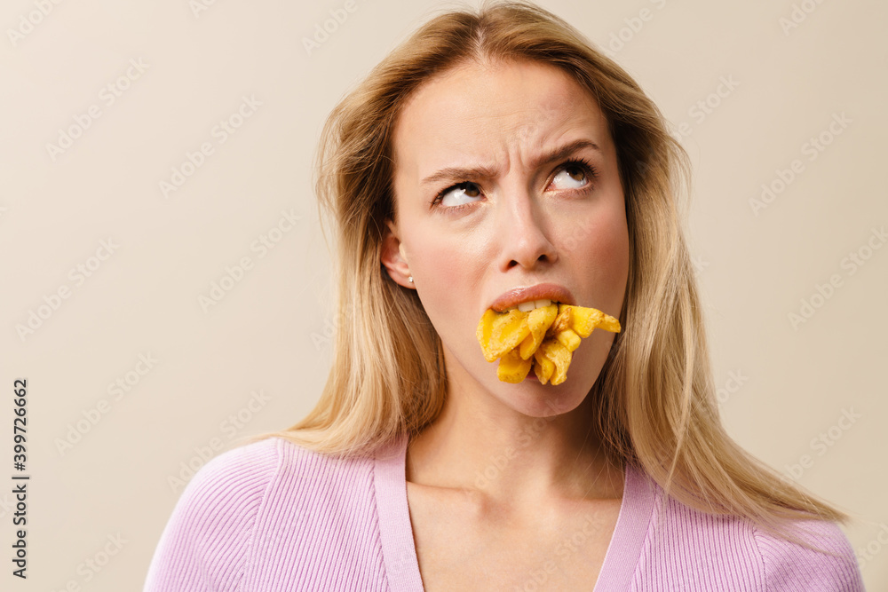 Displeased beautiful girl posing with french fries in her mouth