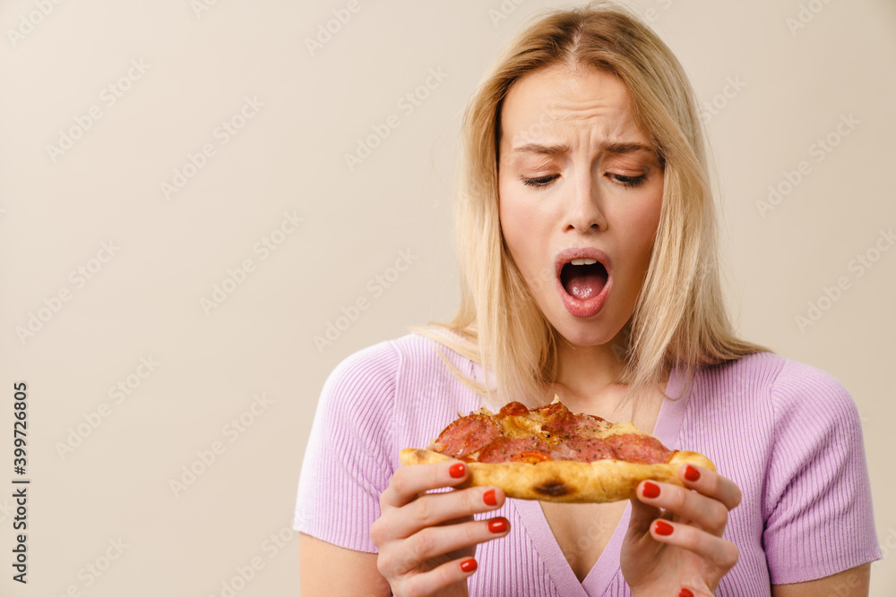 Shocked beautiful blonde girl exclaiming while posing with pizza