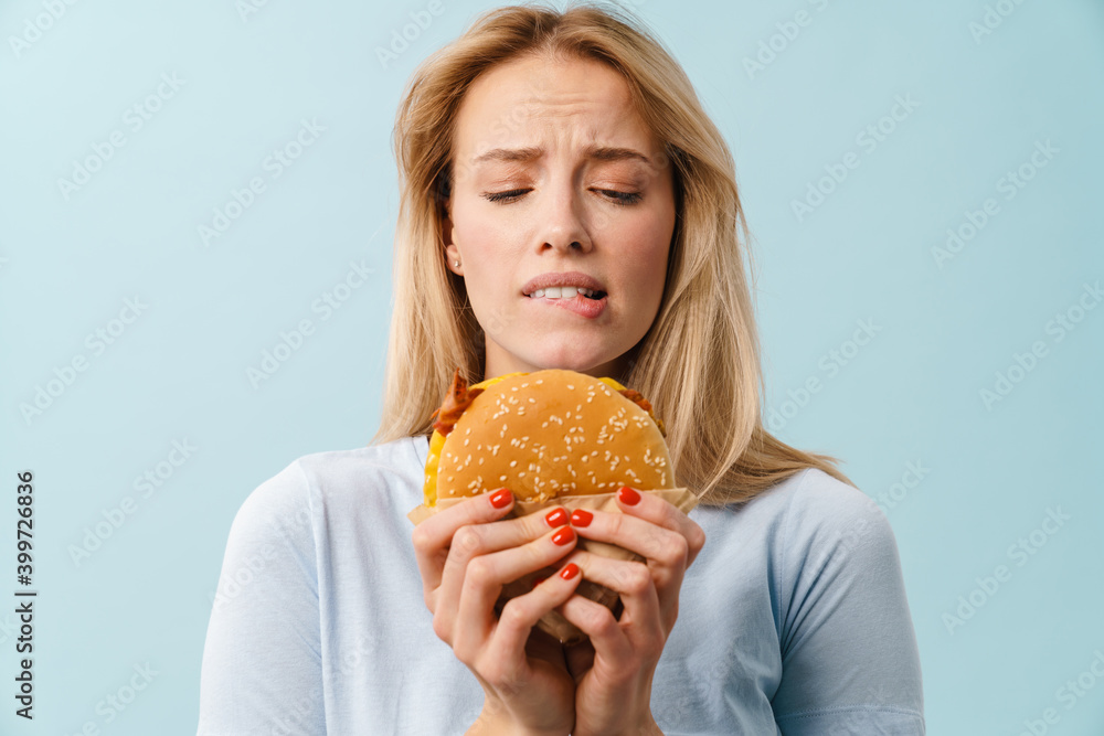 Unhappy beautiful blonde girl posing with hamburger Unhappy beautiful blonde girl posing with hamburger