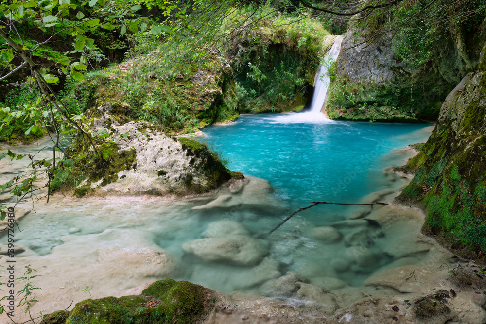 small river of turquoise water with a waterfall that ends in a pond small river of turquoise water with a waterfall that ends in a pond