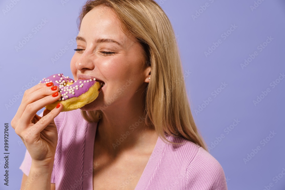 Laughing charming blonde girl eating doughnut on camera
