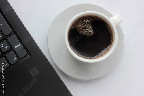 Cup of coffee and laptop on white table. Overhead view. Copy space