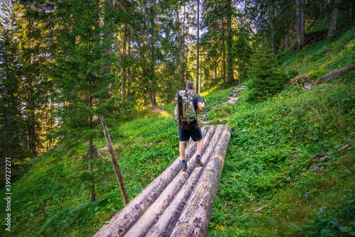 Traveller hiking in the woods wearing backpack and camera tripod