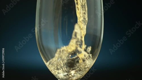 Clouse-up of a transparent glass with a drink pouring in it on a dark blue background in slow motion, 1000fps