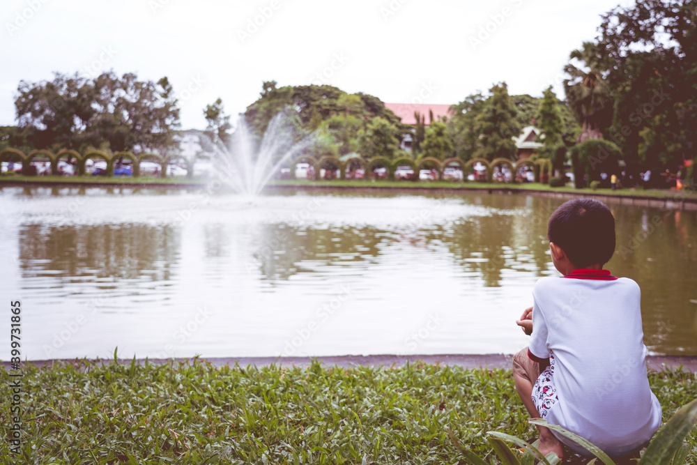 Fototapeta premium A little boy sitting on the edge of the pool, sad concept.