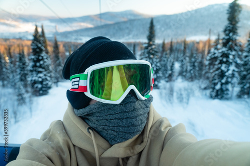 guy in a protective reflective mask from the snow on the background of a picturesque mountain winter nature. Travels alone through the ski resort