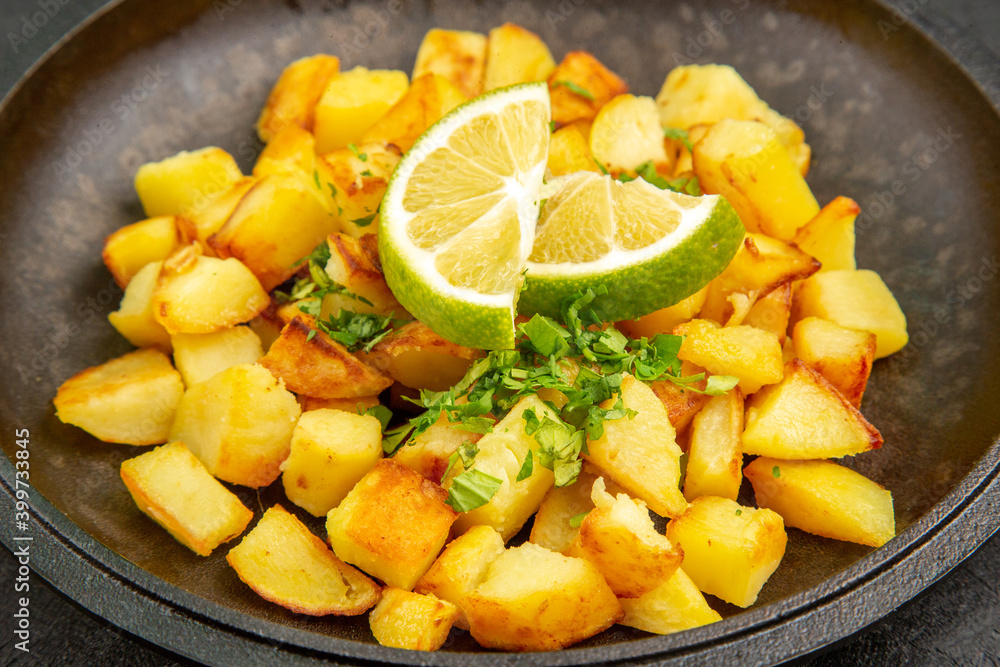 front view tasty fried potatoes inside pan with lemon slices on dark background color calorie cuisine meal food front view tasty fried potatoes inside pan with lemon slices on dark background color calorie cuisine meal food