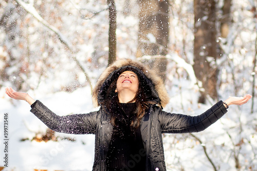 Woman throwing snow nad having fun in snowy forest.