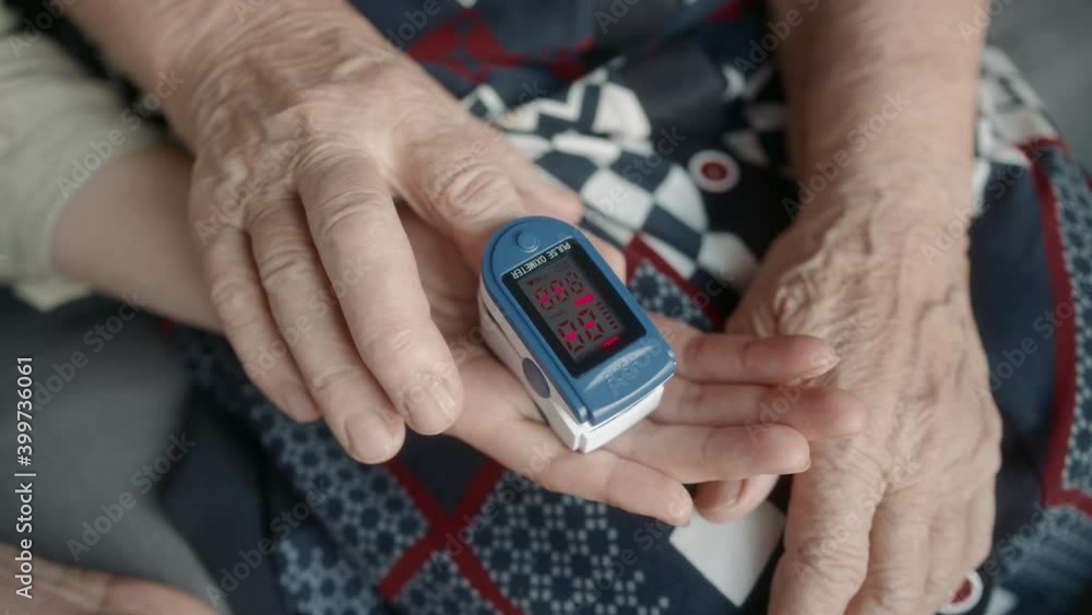 Daughter helps elderly mother measure oxygen levels with a pulse