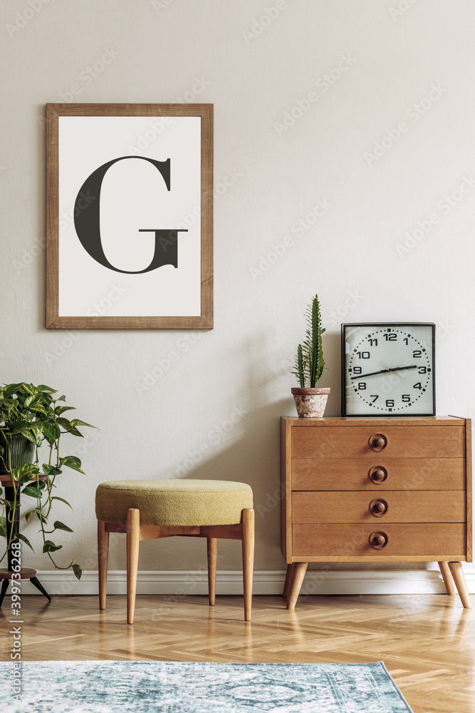 Vintage interior design of living room with design retro pouf and commode,  plants, cacti, black clock and brown mock up poster frame on the beige  wall. Stylish home decor. Template. Photos