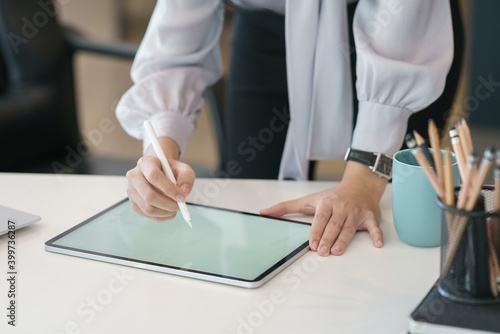 Businesswoman hand working with a stylus pen on a digital tablet with a laptop computer in a modern office.