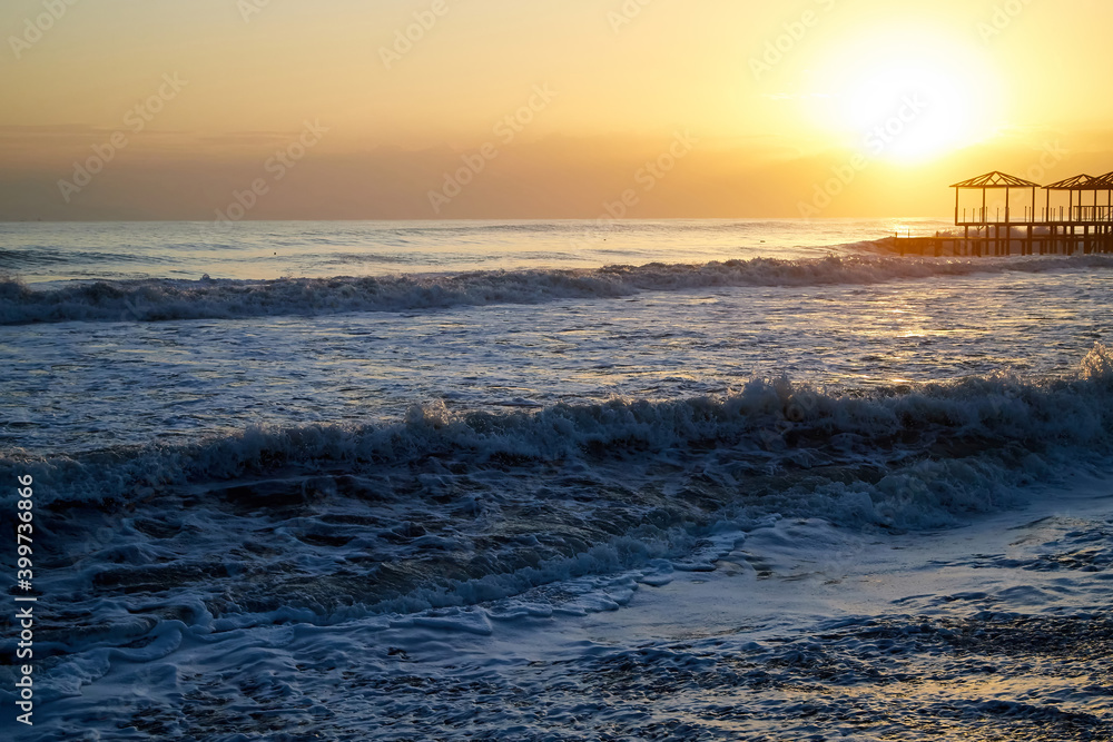 Water of sea, waves with white foam, pierce and sky with sunset in a nice evening.