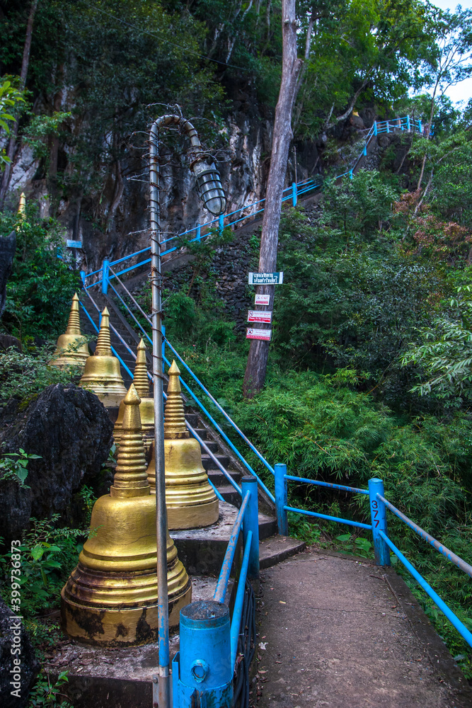 Steep concrete staircase to the rock and golden Buddhist stupas nearby. The lantern is wrapped in barbed wire from monkeys. Lots of green trees. Steep concrete staircase to the rock and golden Buddhist stupas nearby. The lantern is wrapped in barbed wire from monkeys. Lots of green trees.