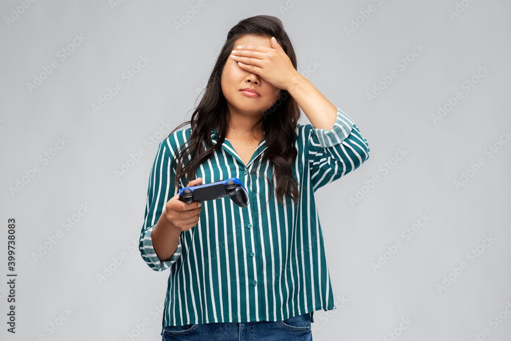 people, leisure and gaming concept - upset asian young woman playing video game with gamepad over grey background people, leisure and gaming concept - upset asian young woman playing video game with gamepad over grey background
