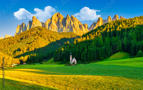 Dolomites mountains at golden hour with St Johann Church in Santa Maddalena, Val Di Funes village , Italy photo